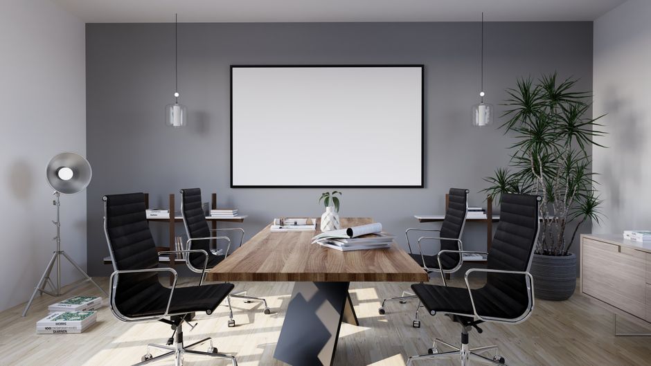 Sleek meeting room featuring black chairs, wooden table, and a blank screen, ideal for business settings.